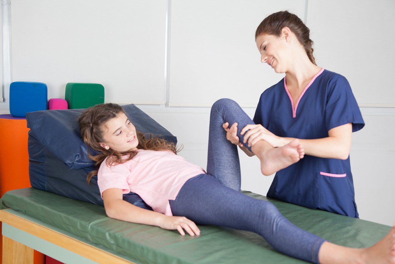 Girl on exam table with nurse lifting her left leg