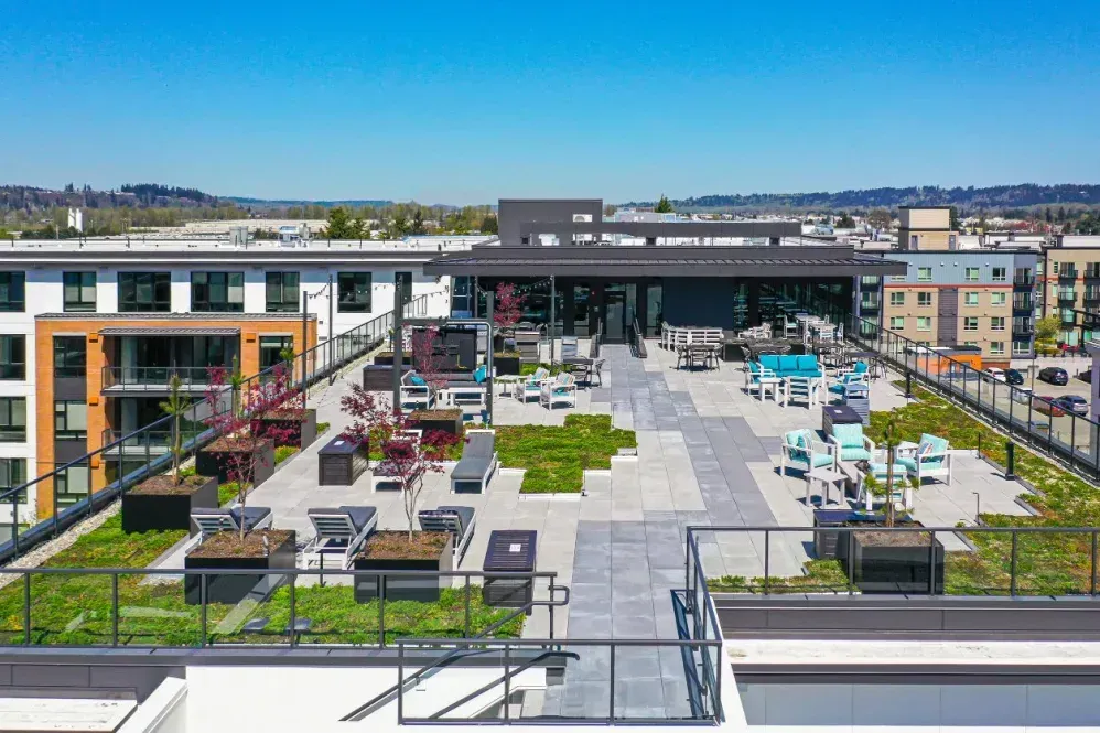Rooftop patio with seating, landscaping, and building. Blue sky in the background at The Verge in Auburn, WA.