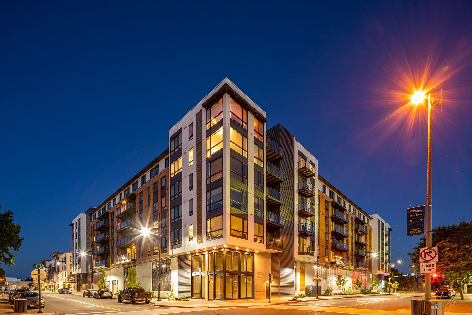 Modern multi-story apartment building at dusk; streetlights illuminate the exterior, reflecting in the windows at The Verge in Auburn, WA
