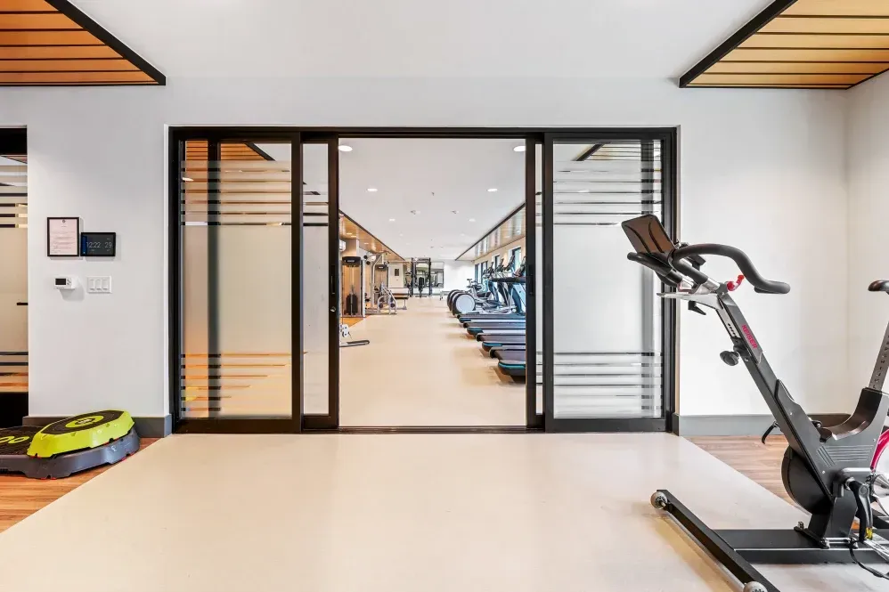 Gym interior with sliding glass doors, exercise bikes, and treadmills visible in the distance at The Verge in Auburn, WA.