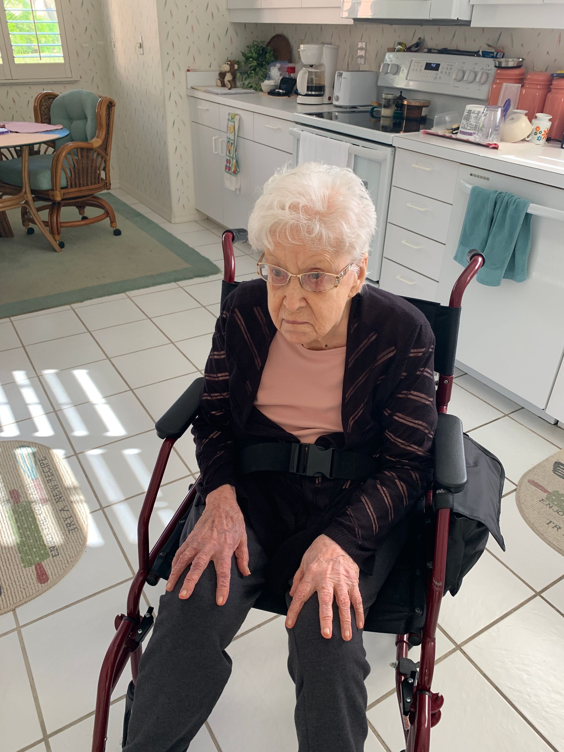An elderly woman is sitting in a wheelchair in a kitchen