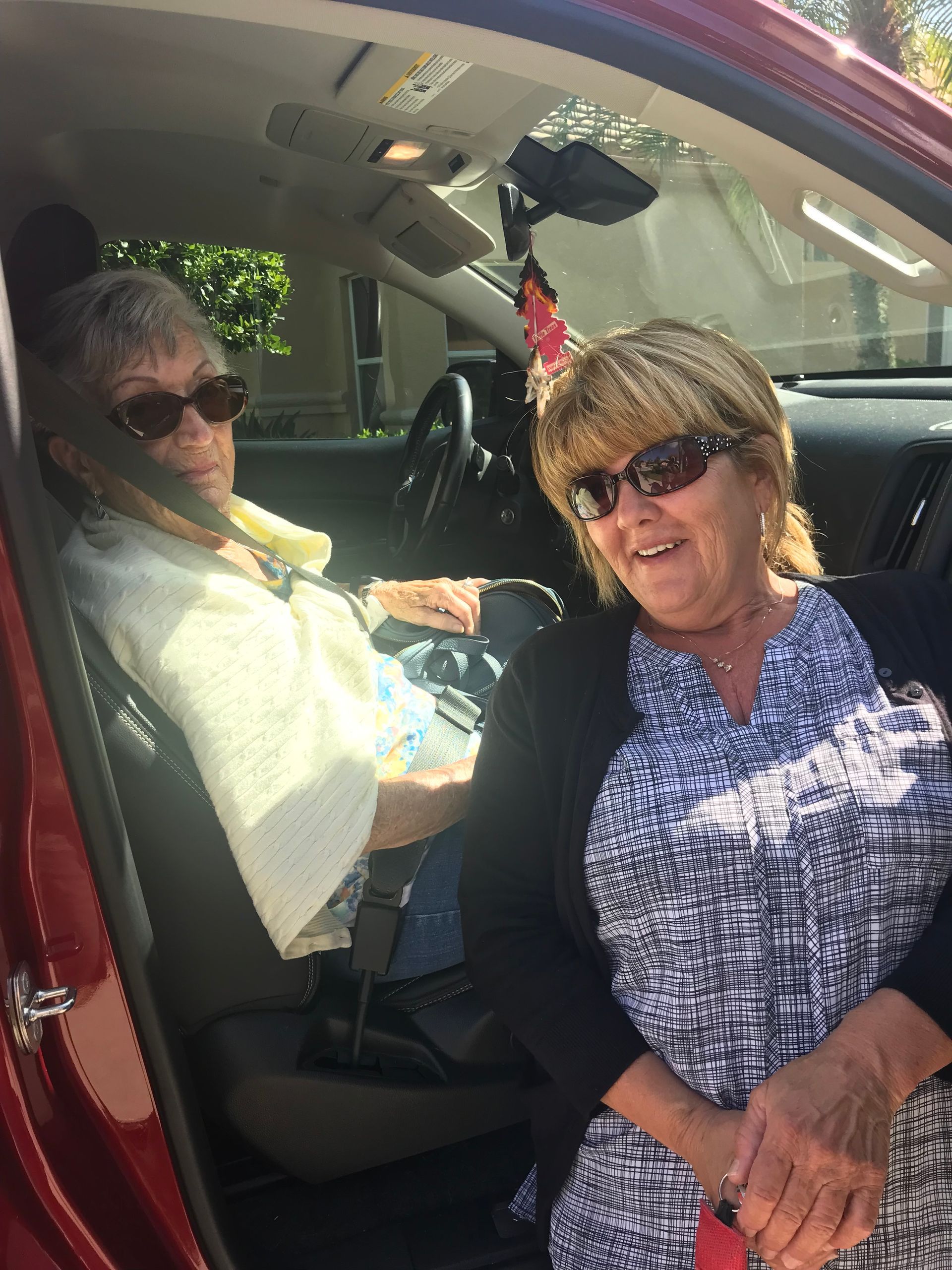 Two women are sitting in the back seat of a car.