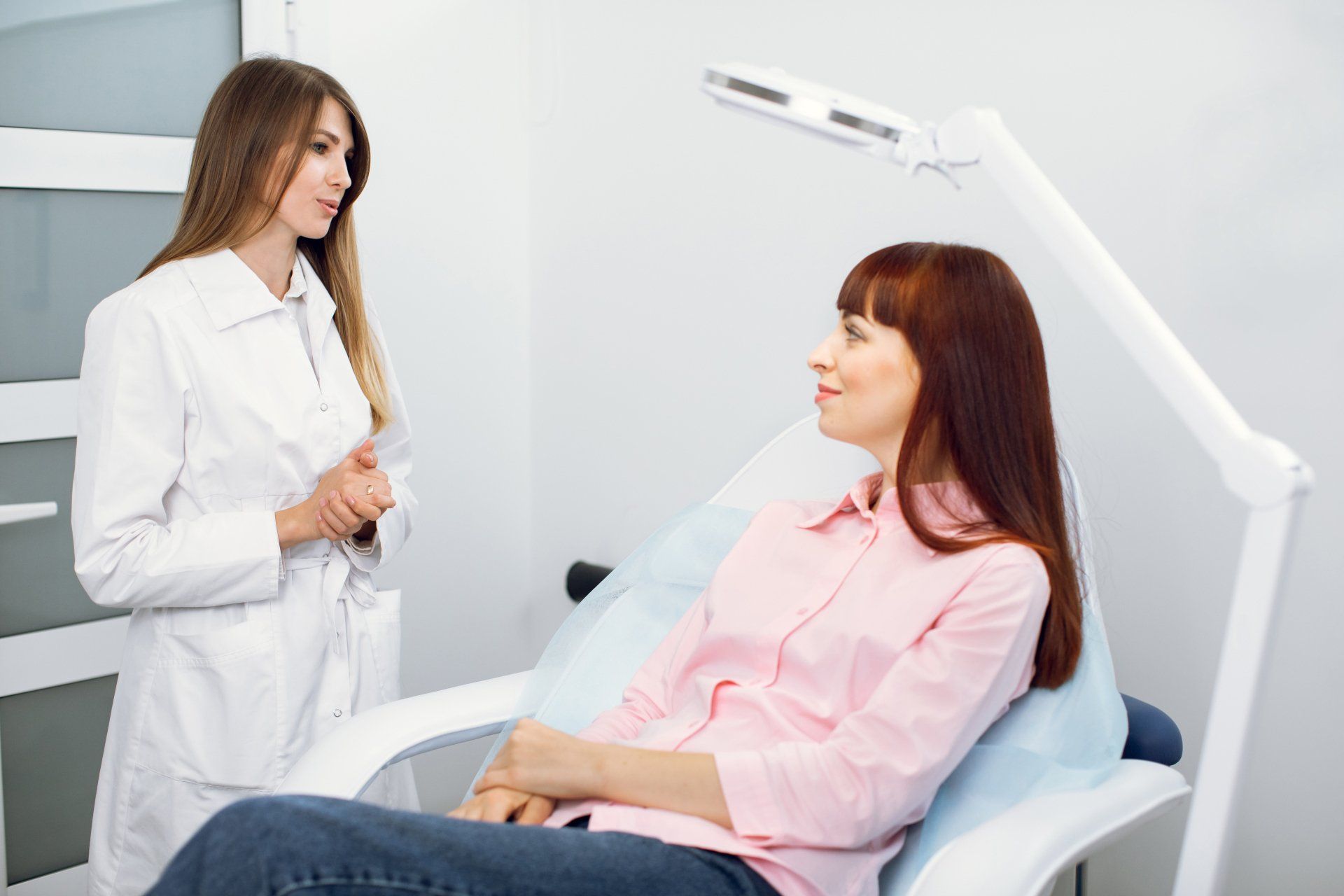 Una mujer está sentada en una silla hablando con un médico.