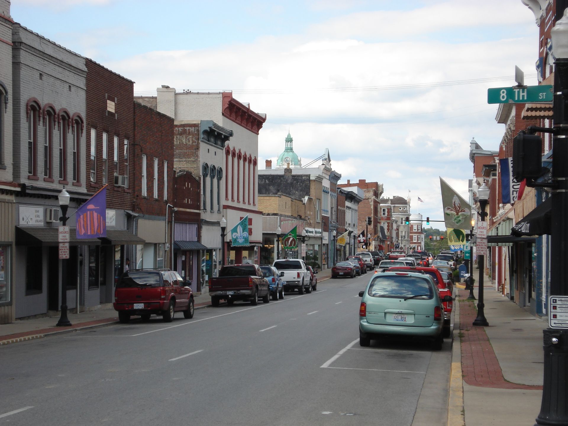 A city street with a green sign that says 8th street