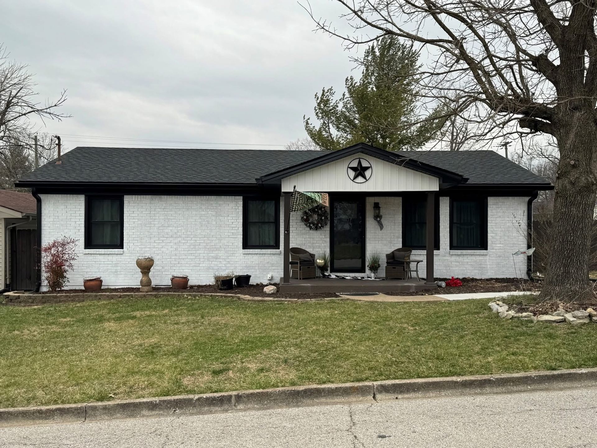 A white house with a black roof and a star on the front porch.