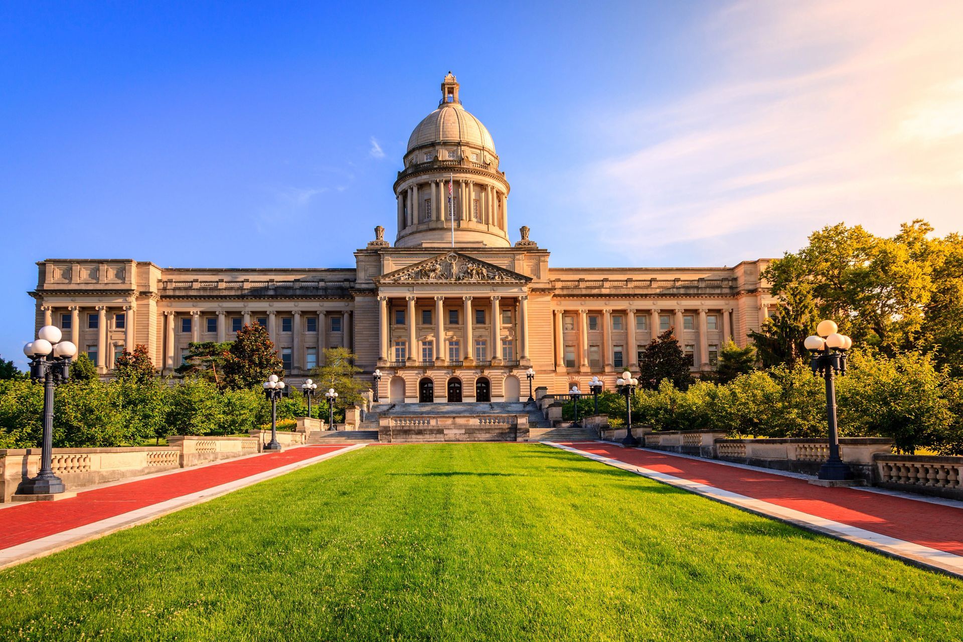 A large building with a dome on top of it and a large lawn in front of it.