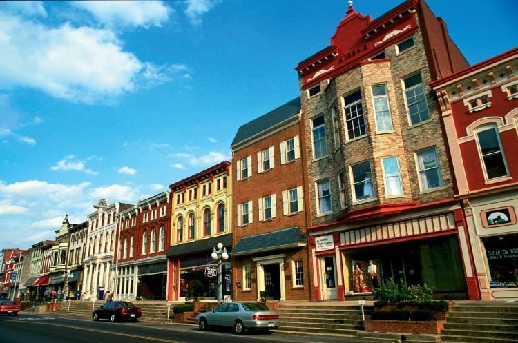 A row of brick buildings with cars parked in front of them