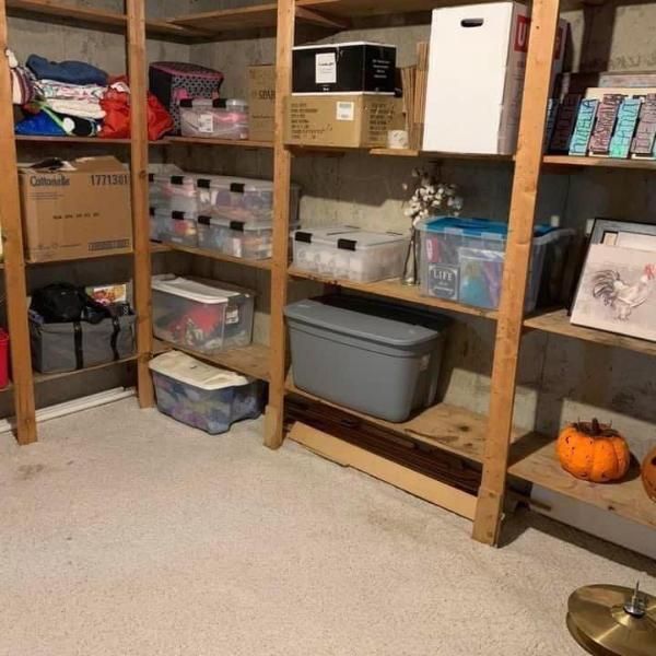 Wooden shelves in a basement, holding boxes, bins, and other storage items.
