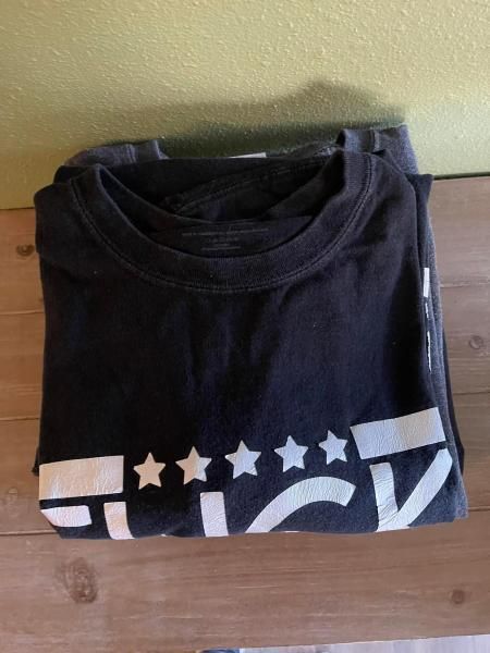 Folded black t-shirt with white text that says 