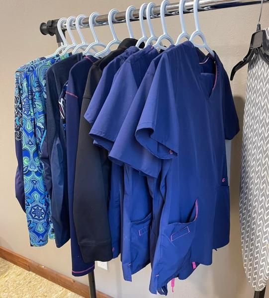 Clothes on hangers, various shades of blue and black scrub tops.