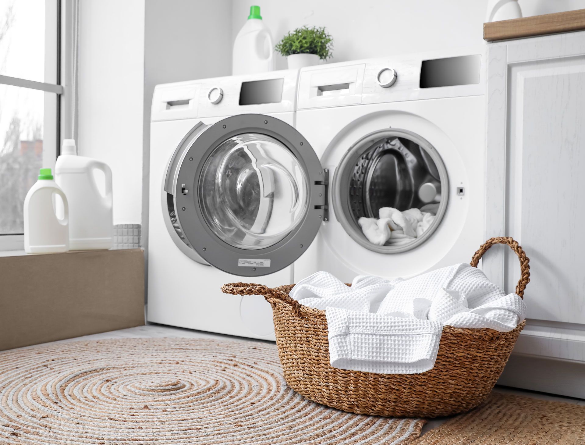 Laundry room with washing machines, laundry basket, and detergent.