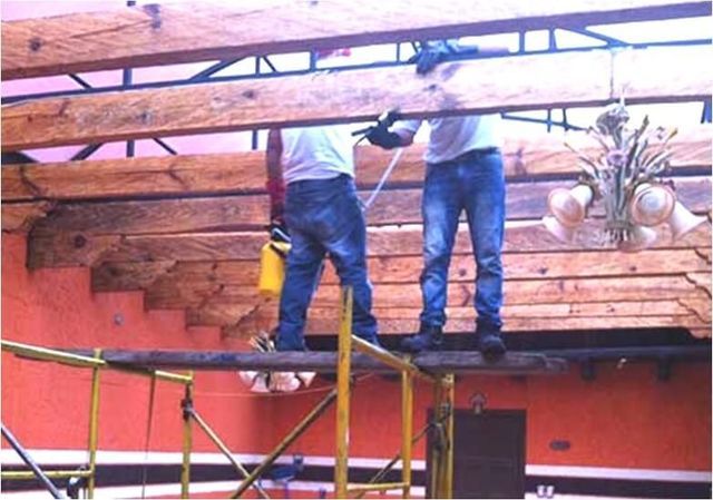 Dos hombres están trabajando en una estructura de madera sobre un andamio