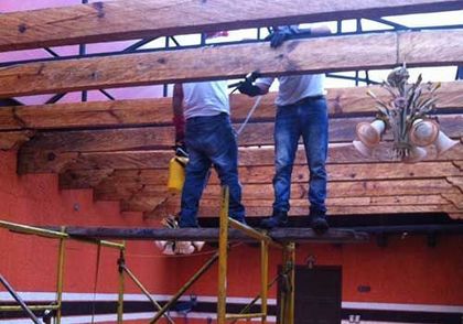 Dos hombres están trabajando en una estructura de madera sobre un andamio