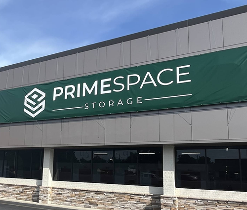 PrimeSpace Storage building with green and white sign under blue sky.