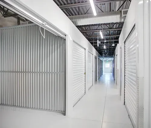 Interior of a storage facility hallway with several closed units and one open unit.