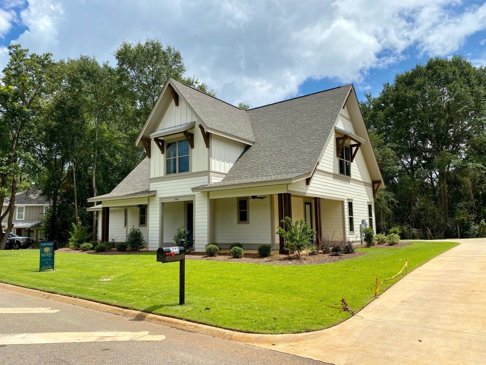 A white house with a gray roof is sitting on top of a lush green lawn.