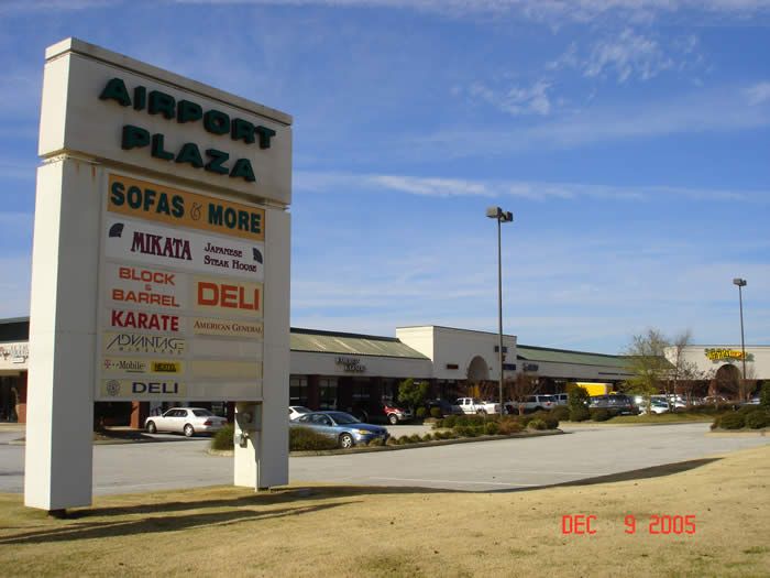A sign for airport plaza sits in front of a shopping center