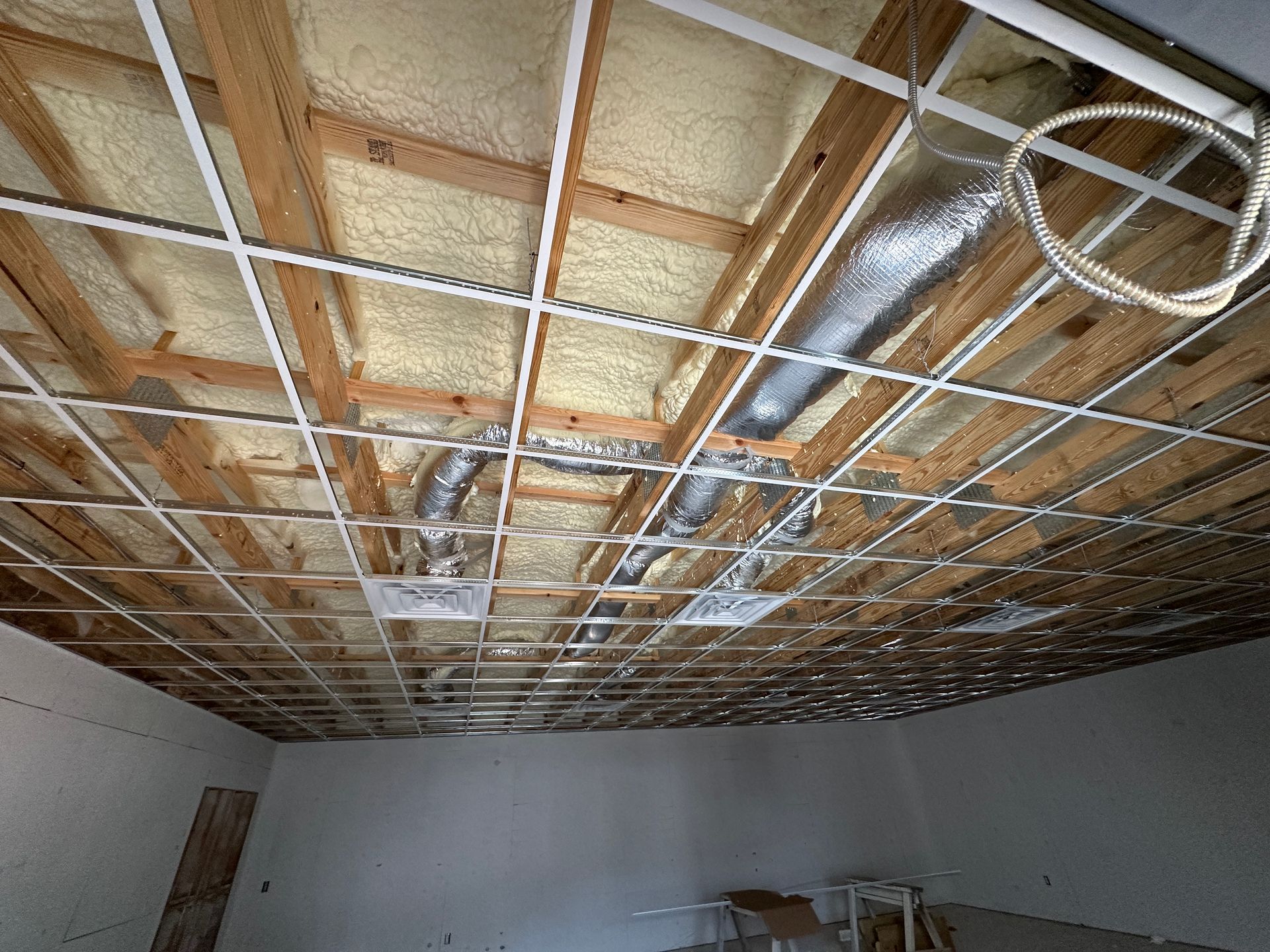 The ceiling of a room is being built and has a lot of wires coming out of it.