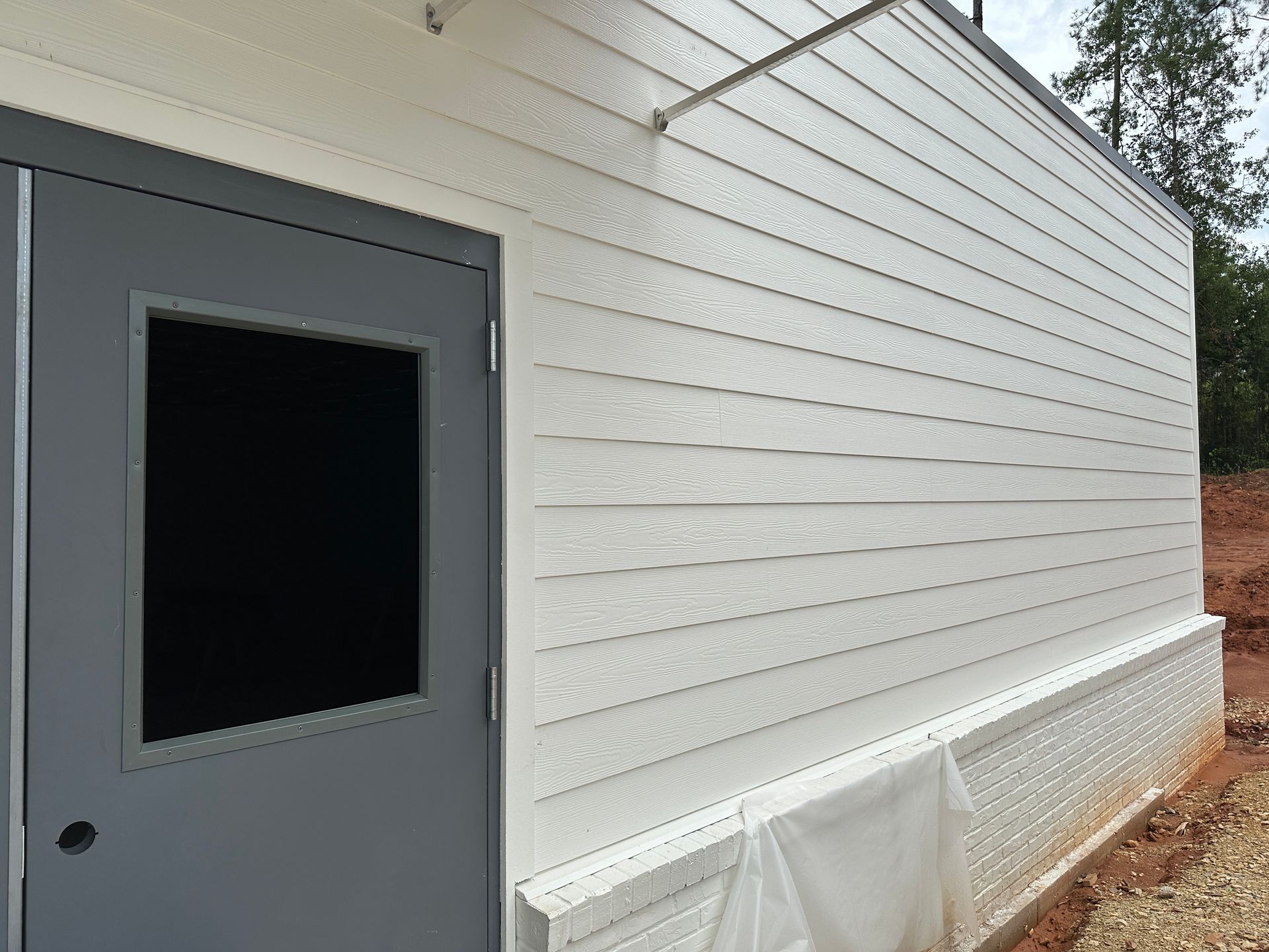 A white building with a gray door and a window.
