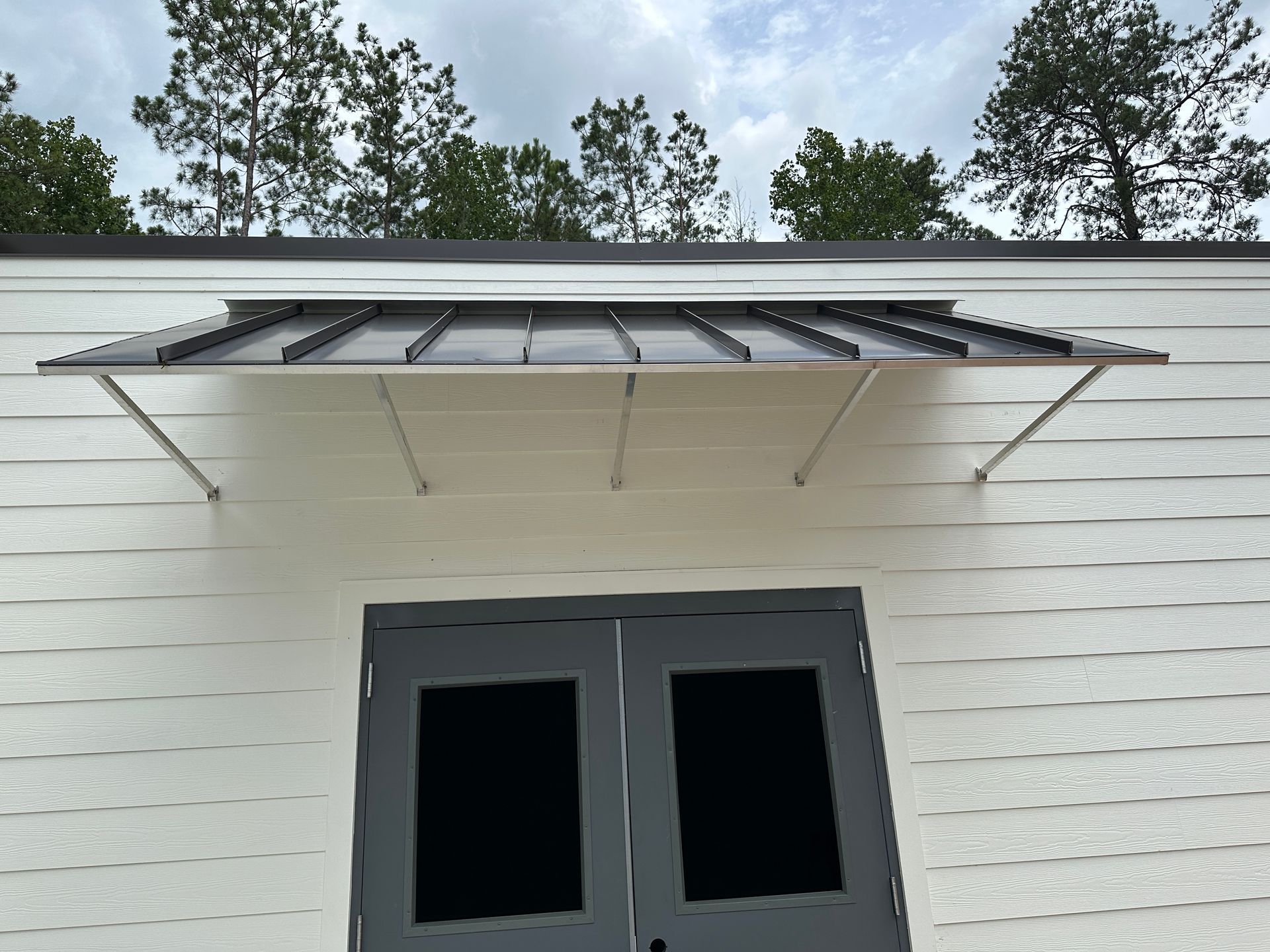 A door with a canopy over it and trees in the background