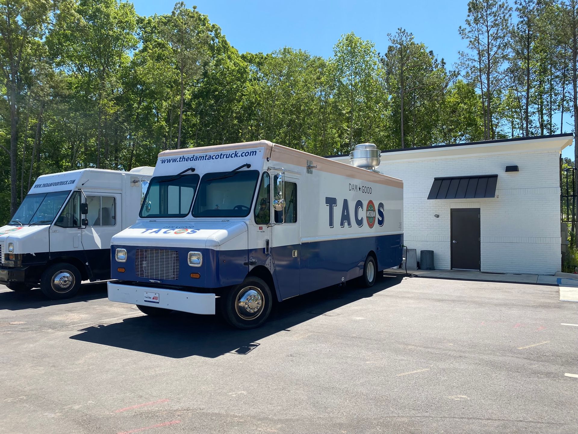 Two tacos food trucks are parked in front of a building
