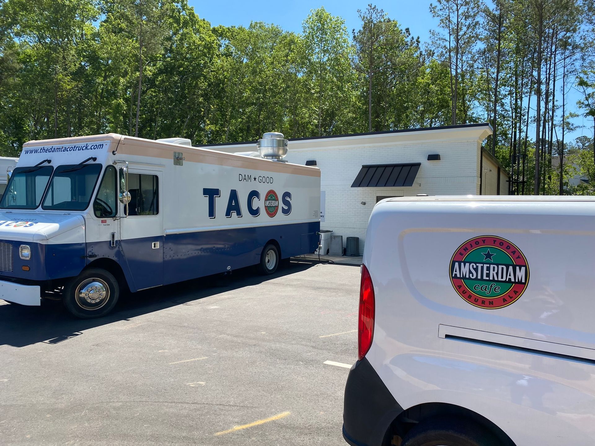 Two food trucks are parked next to each other in a parking lot.