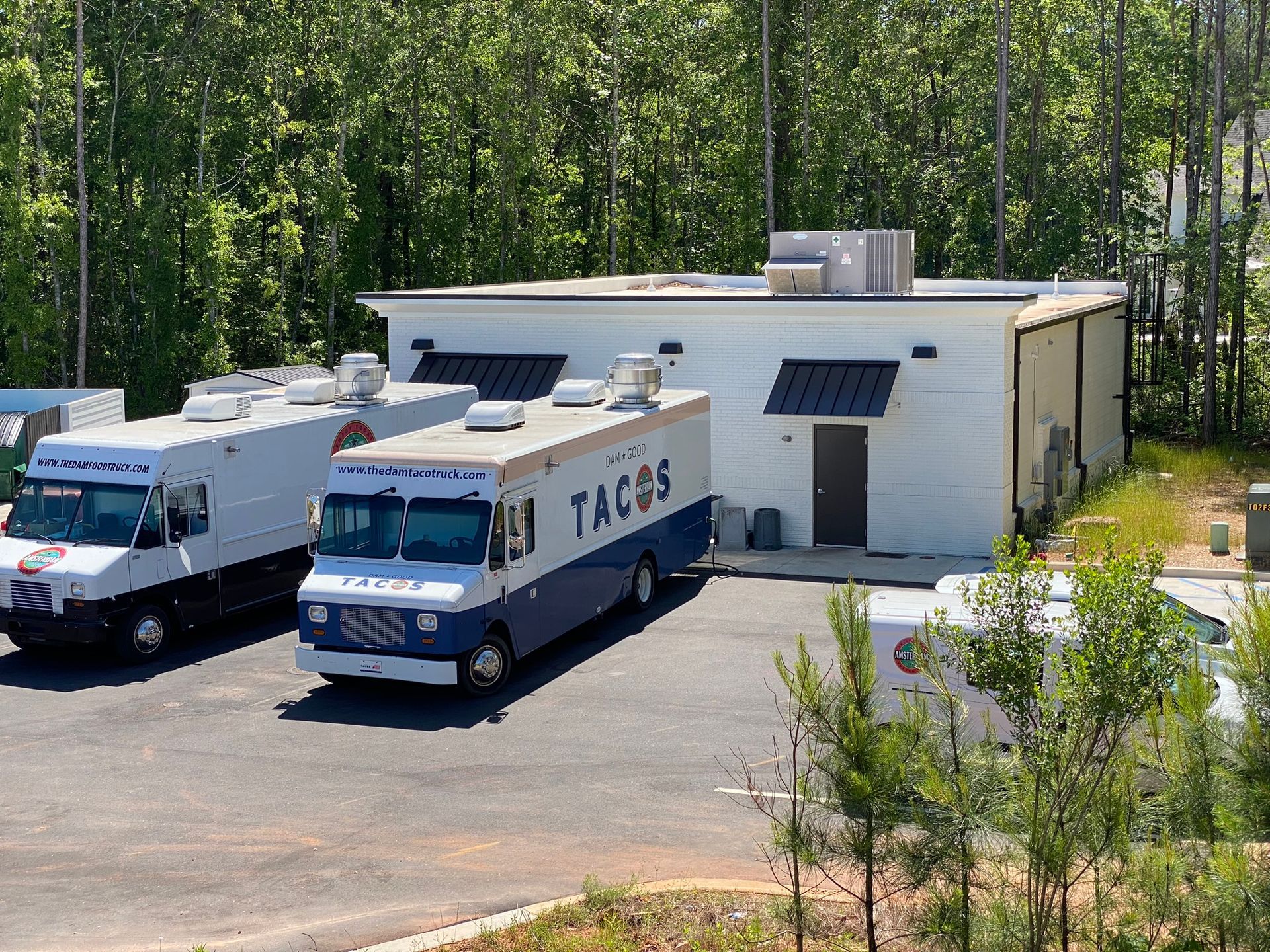 Two tacos food trucks are parked in front of a building