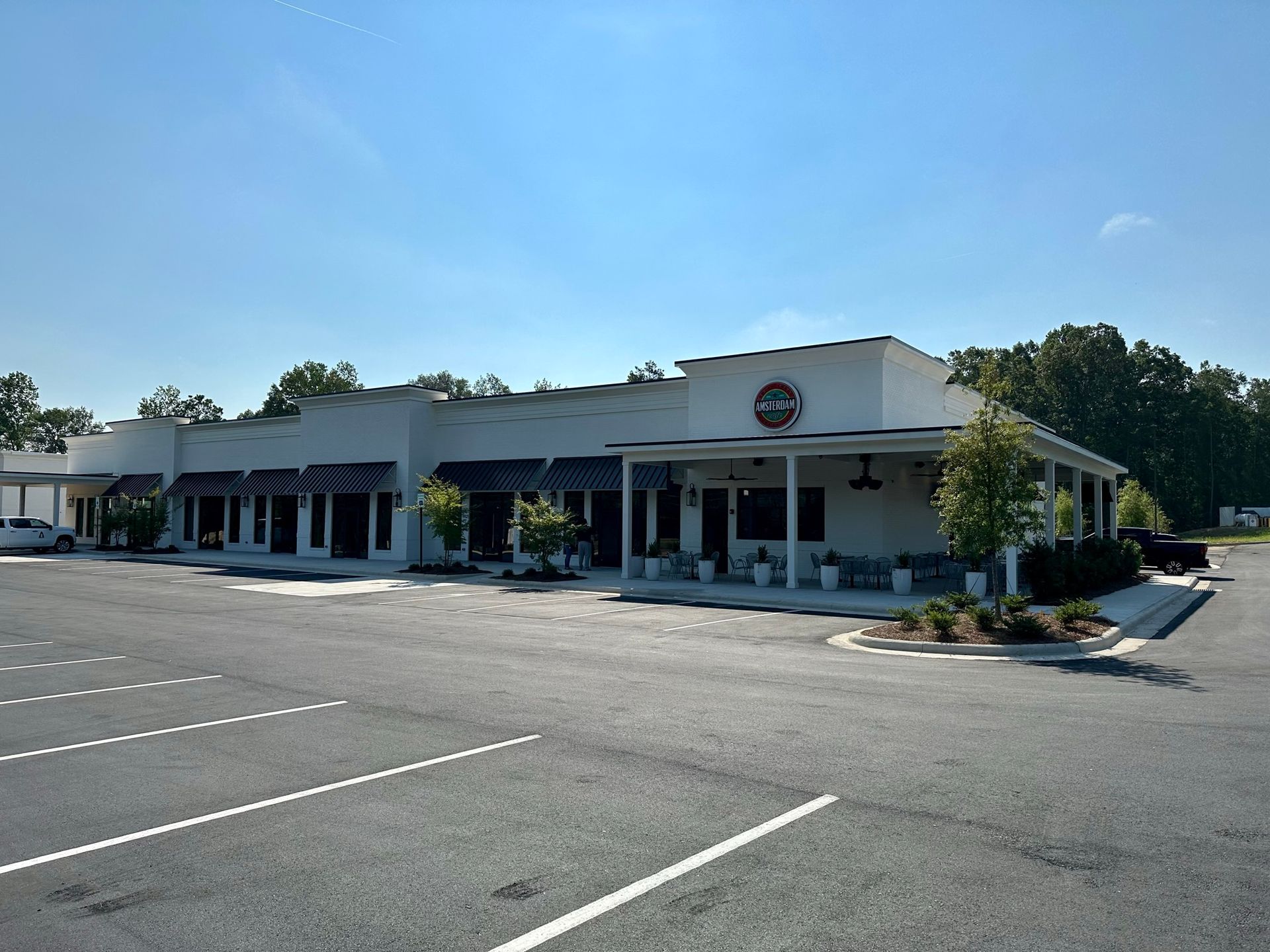 A large white building with a porch and a parking lot in front of it.