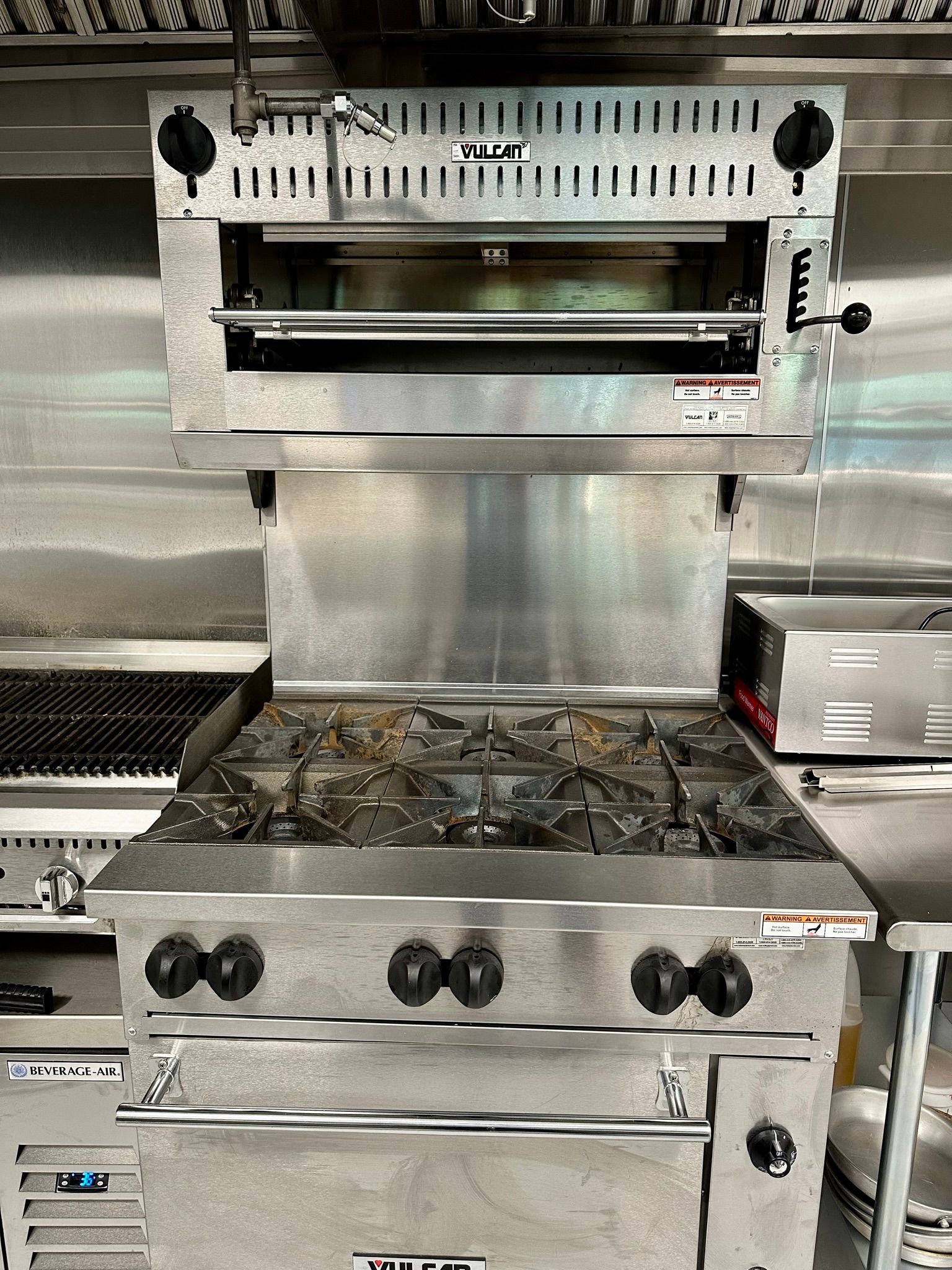 A stainless steel oven is sitting on top of a stove in a kitchen.