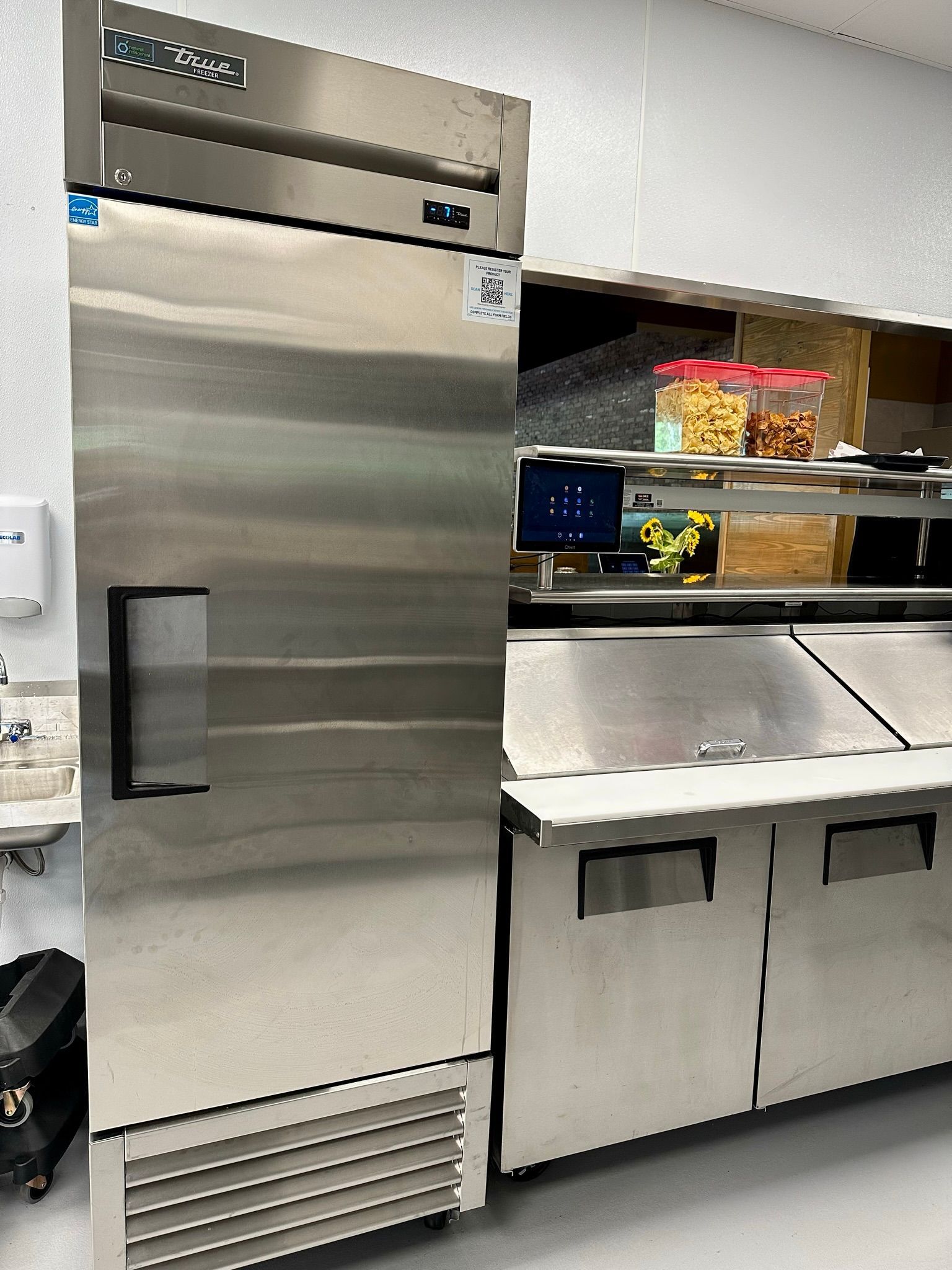 A stainless steel refrigerator is sitting in a kitchen next to a sink.