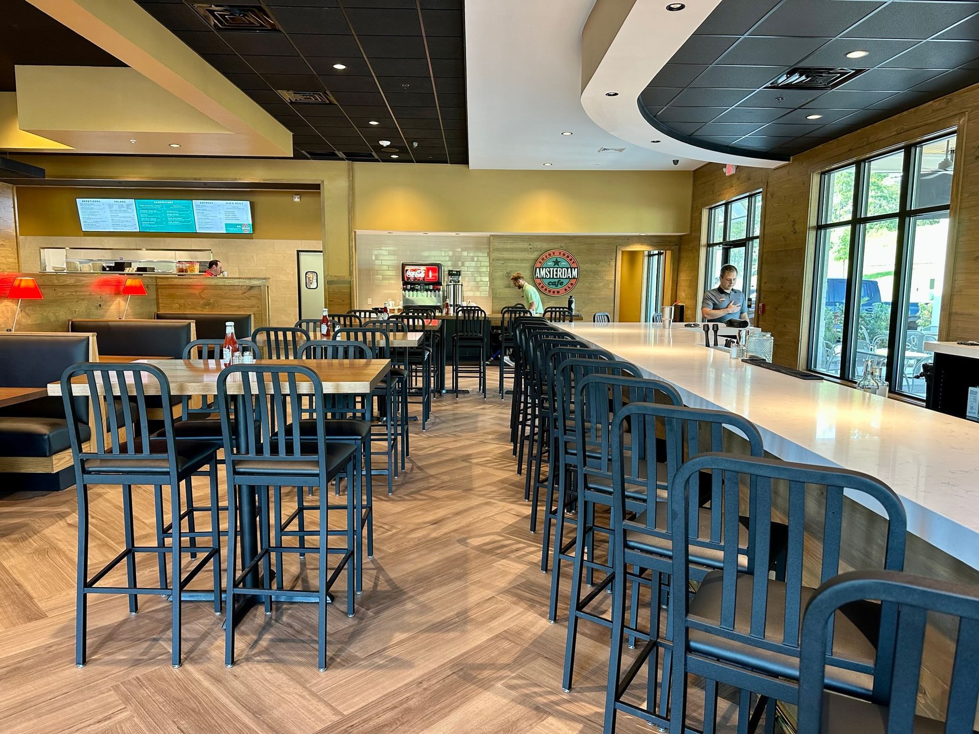 A restaurant with tables and chairs and a long bar.