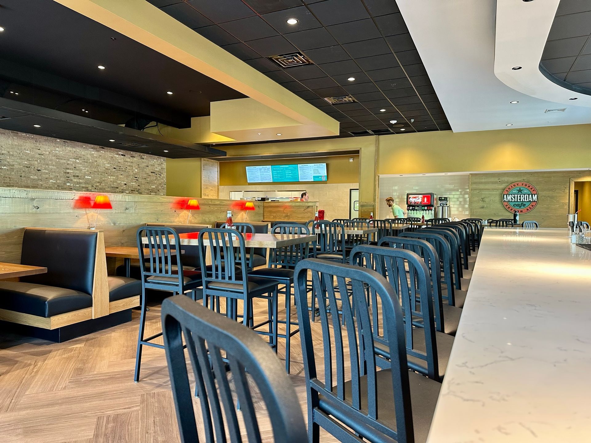 A restaurant with tables and chairs and a long bar.