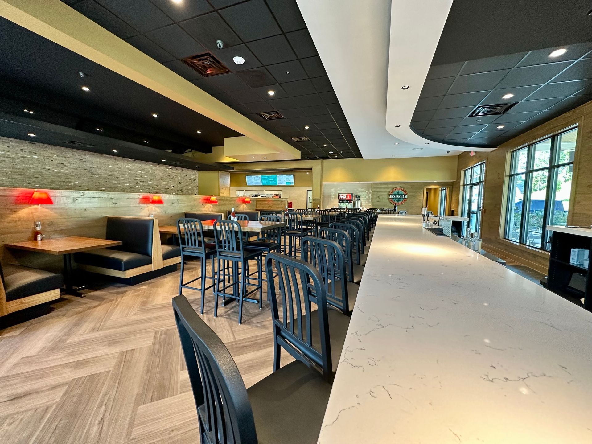 A restaurant with tables and chairs and a long bar.