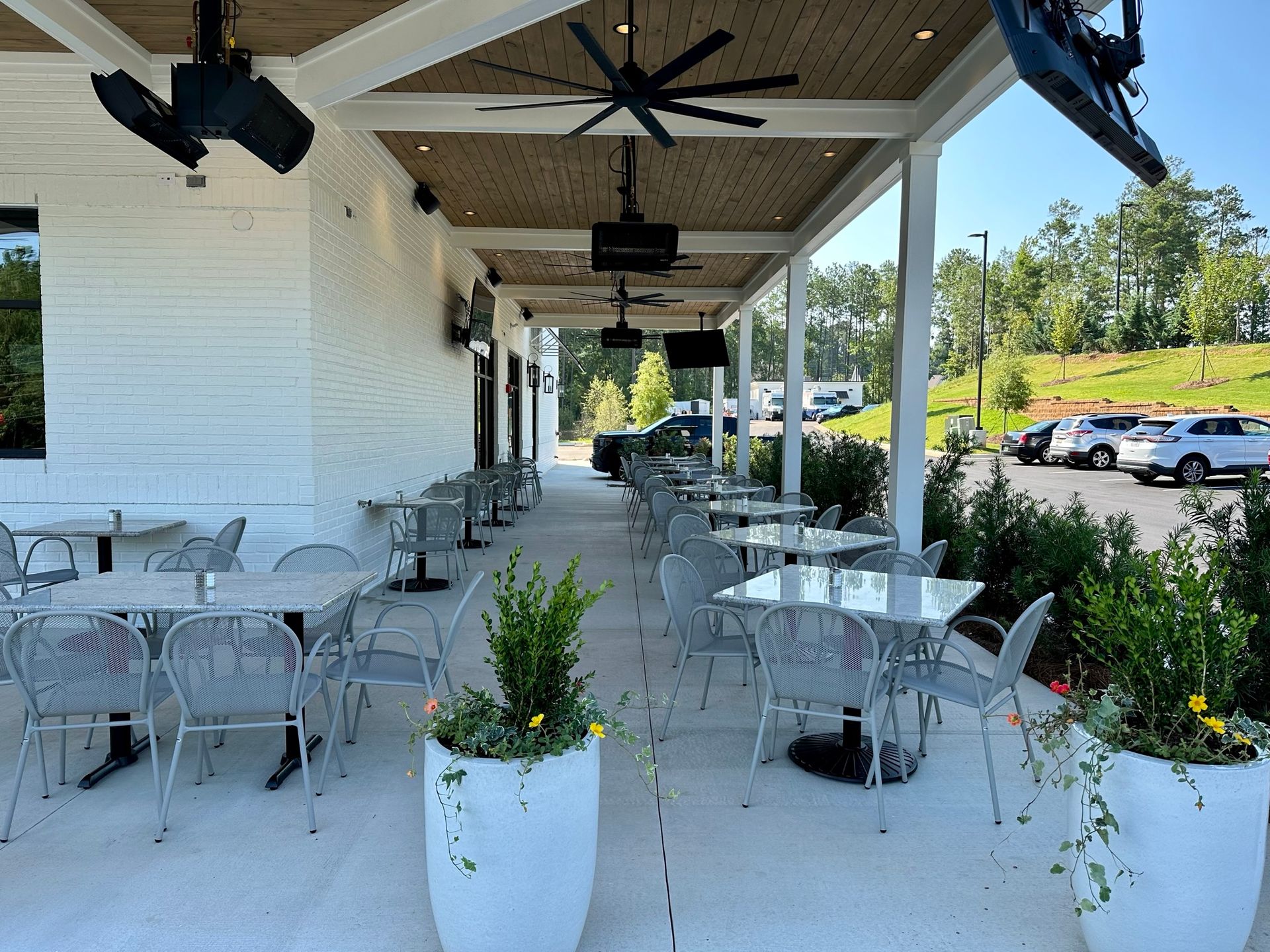 A patio with tables and chairs under a canopy with a ceiling fan.