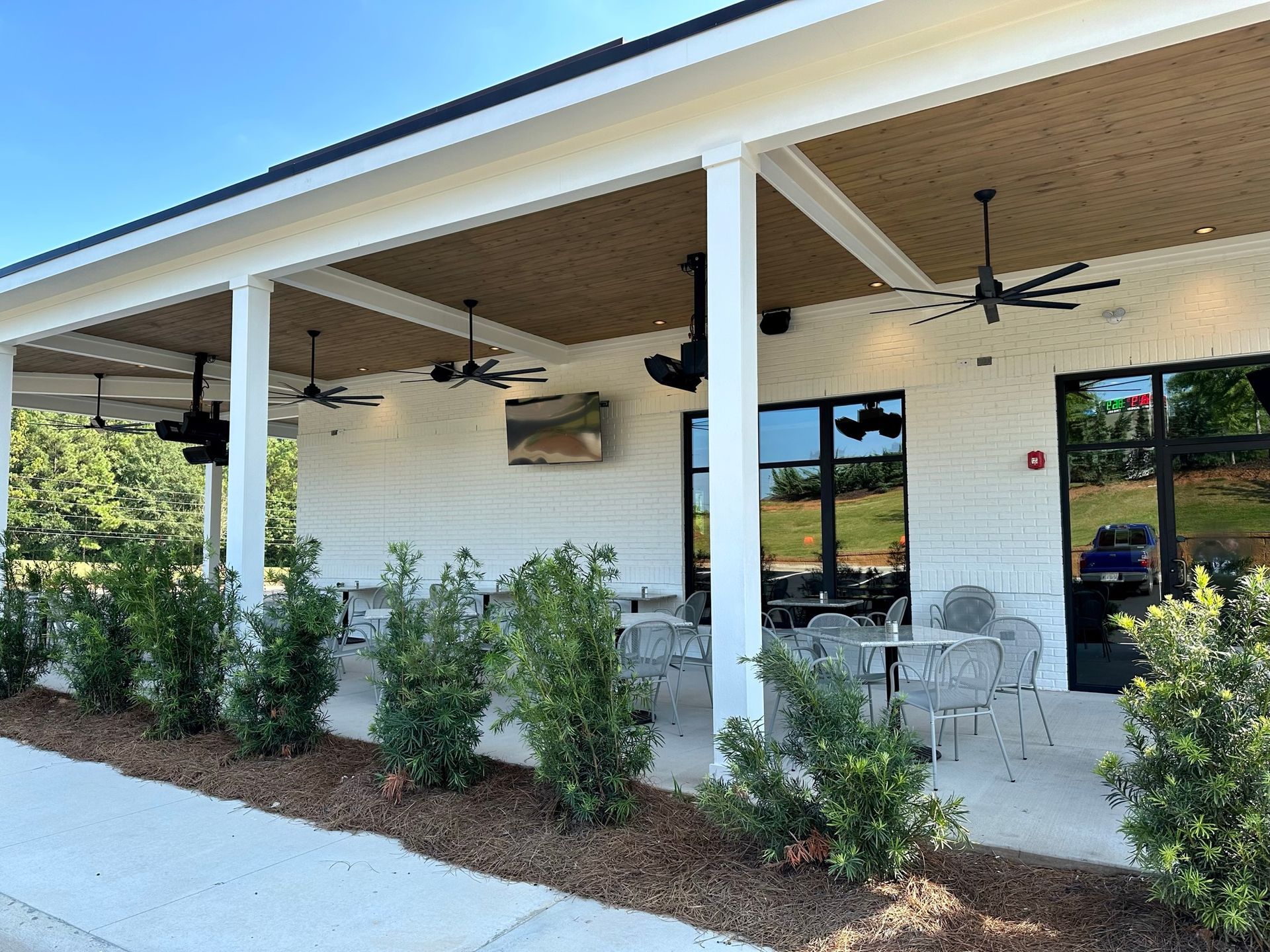 A restaurant with tables and chairs under a covered porch.