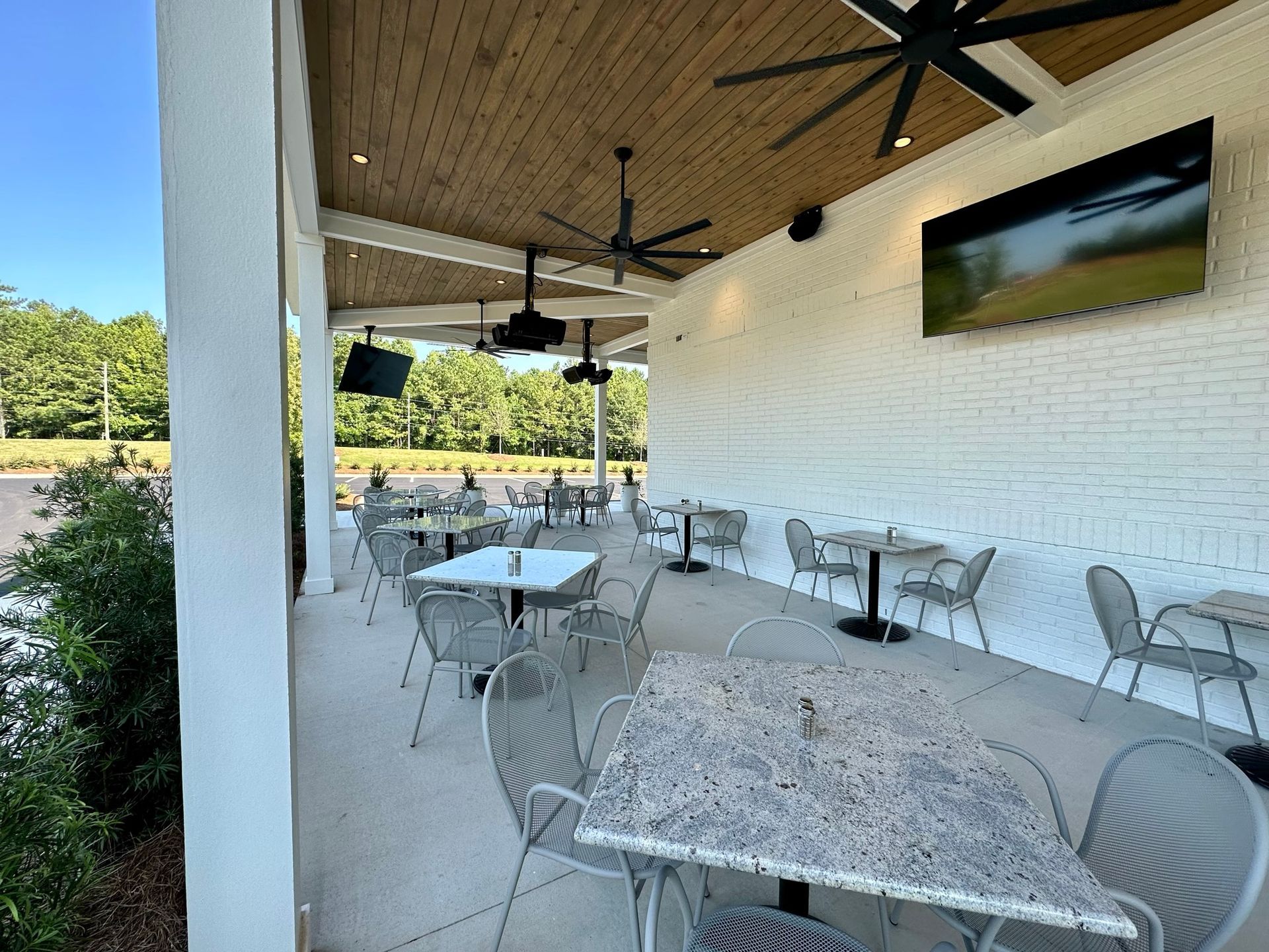 A patio area with tables and chairs under a ceiling fan.