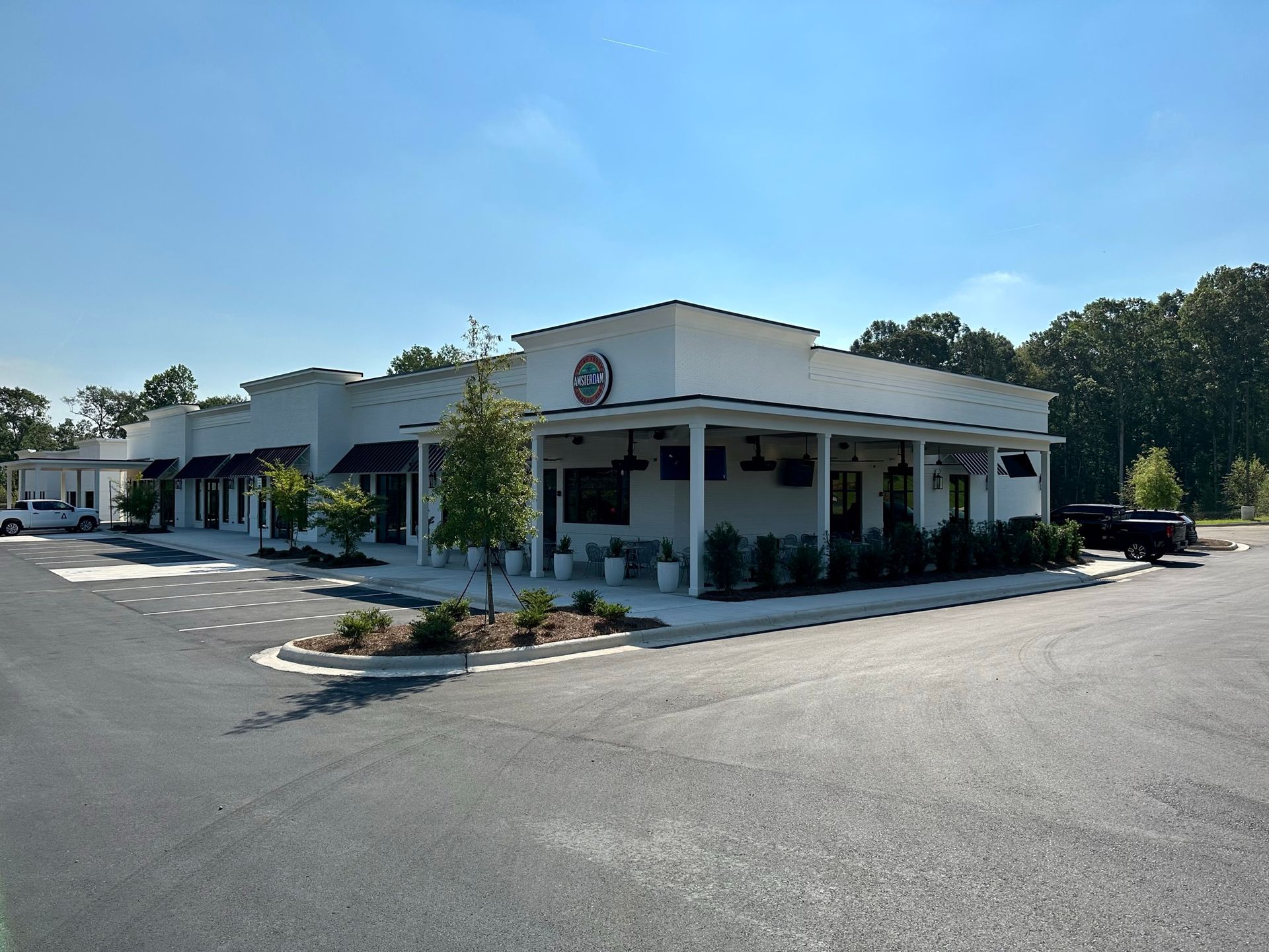 A white building with a porch and a car parked in front of it.