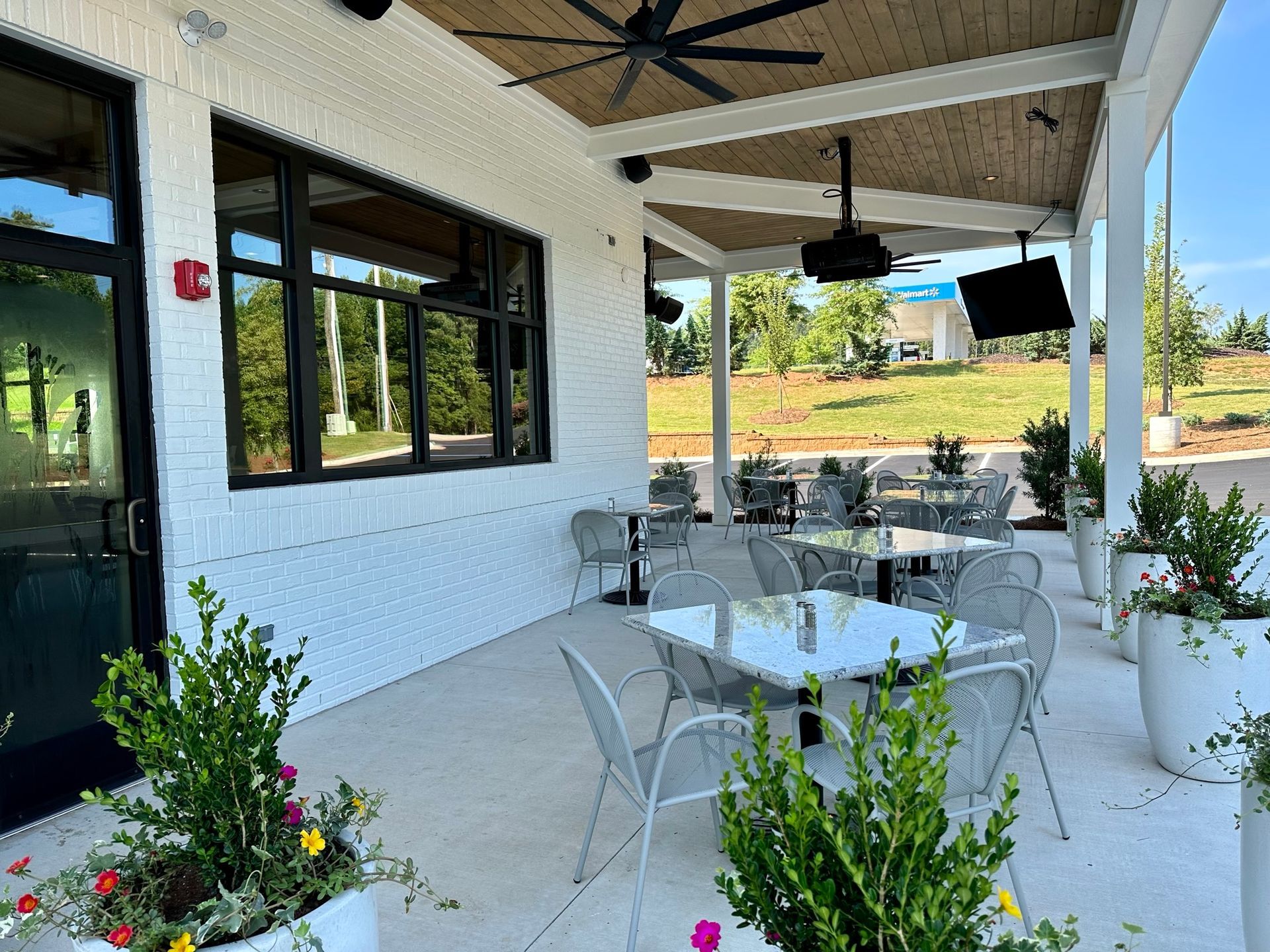A patio with tables and chairs under a ceiling fan.
