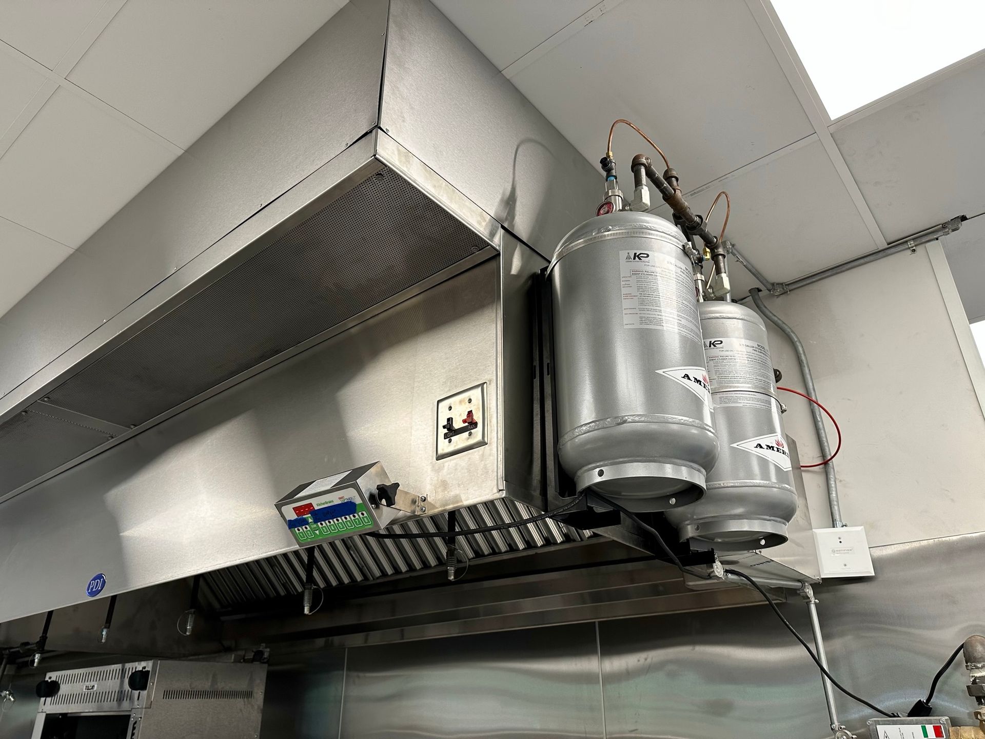 A kitchen with a stainless steel hood and a water heater hanging from the ceiling.