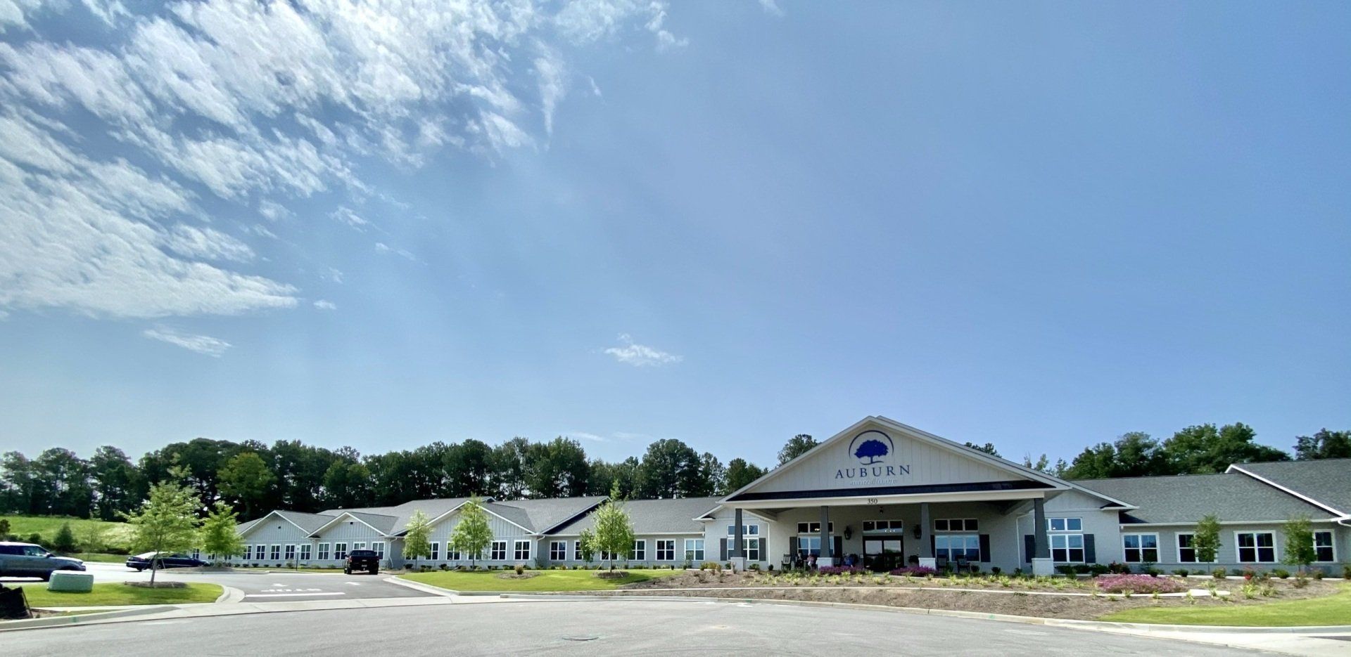 A large building with a blue sky in the background and a lot of cars parked in front of it.
