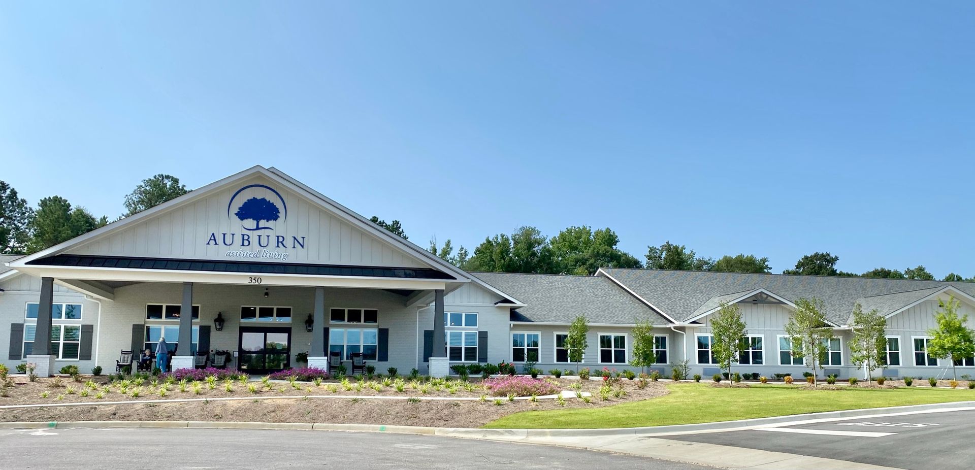 Exterior view of the Auburn facility, a cream-colored building with dark blue accents, and a blue sky overhead.