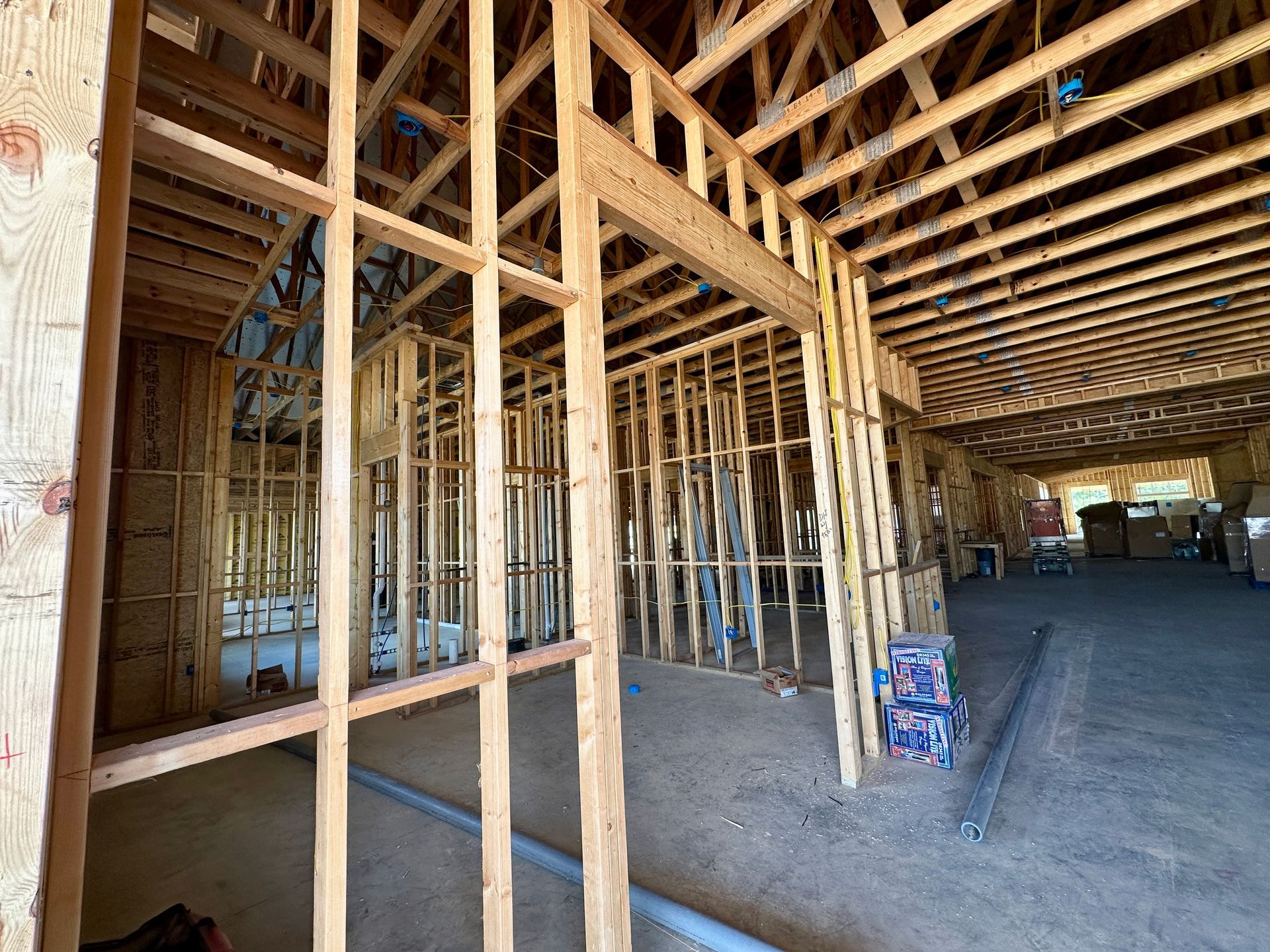 Wooden framework of a building under construction, showing walls and roof supports.
