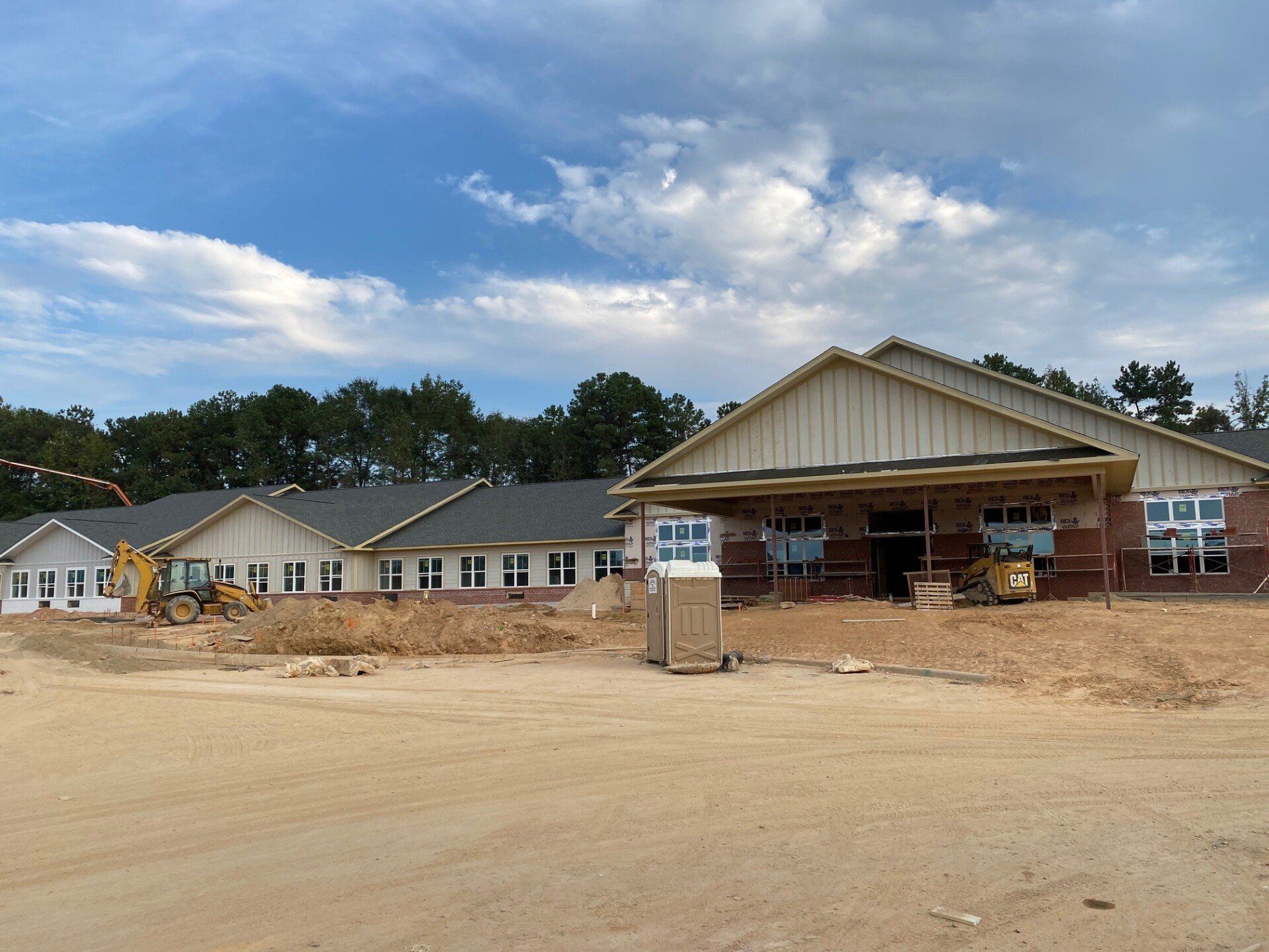 A large building is being built in the middle of a dirt field.