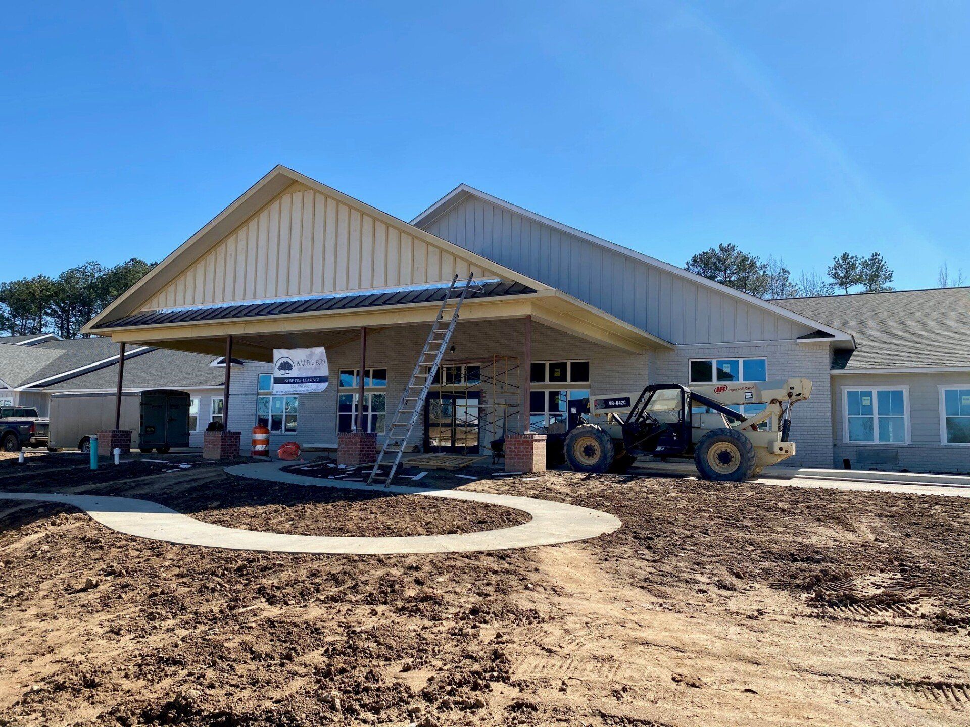 A large house under construction with a bulldozer parked in front of it.