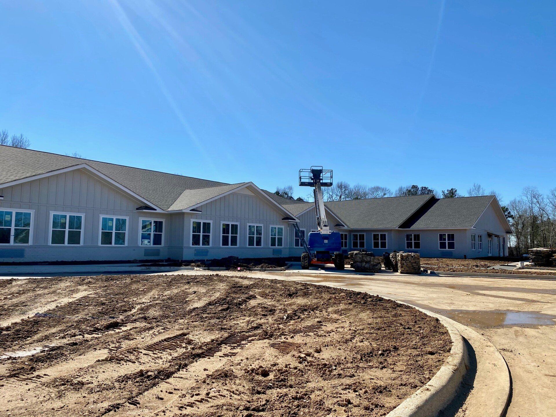 A large white house is being built in the middle of a dirt field.