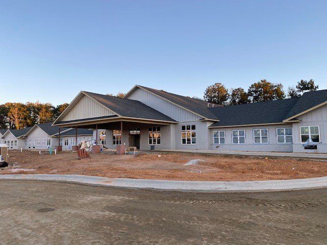 A large white house with a black roof is under construction