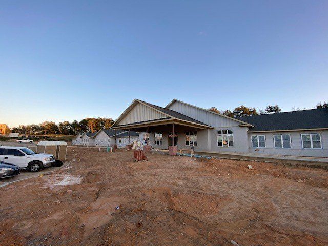 A large building is being built in the middle of a dirt field.
