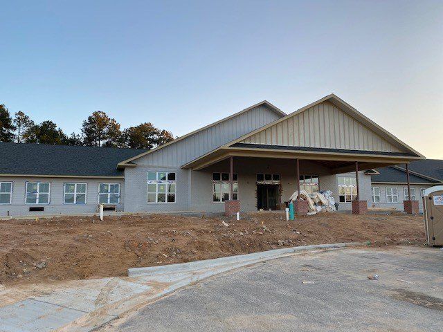 A large white building with a black roof is under construction.
