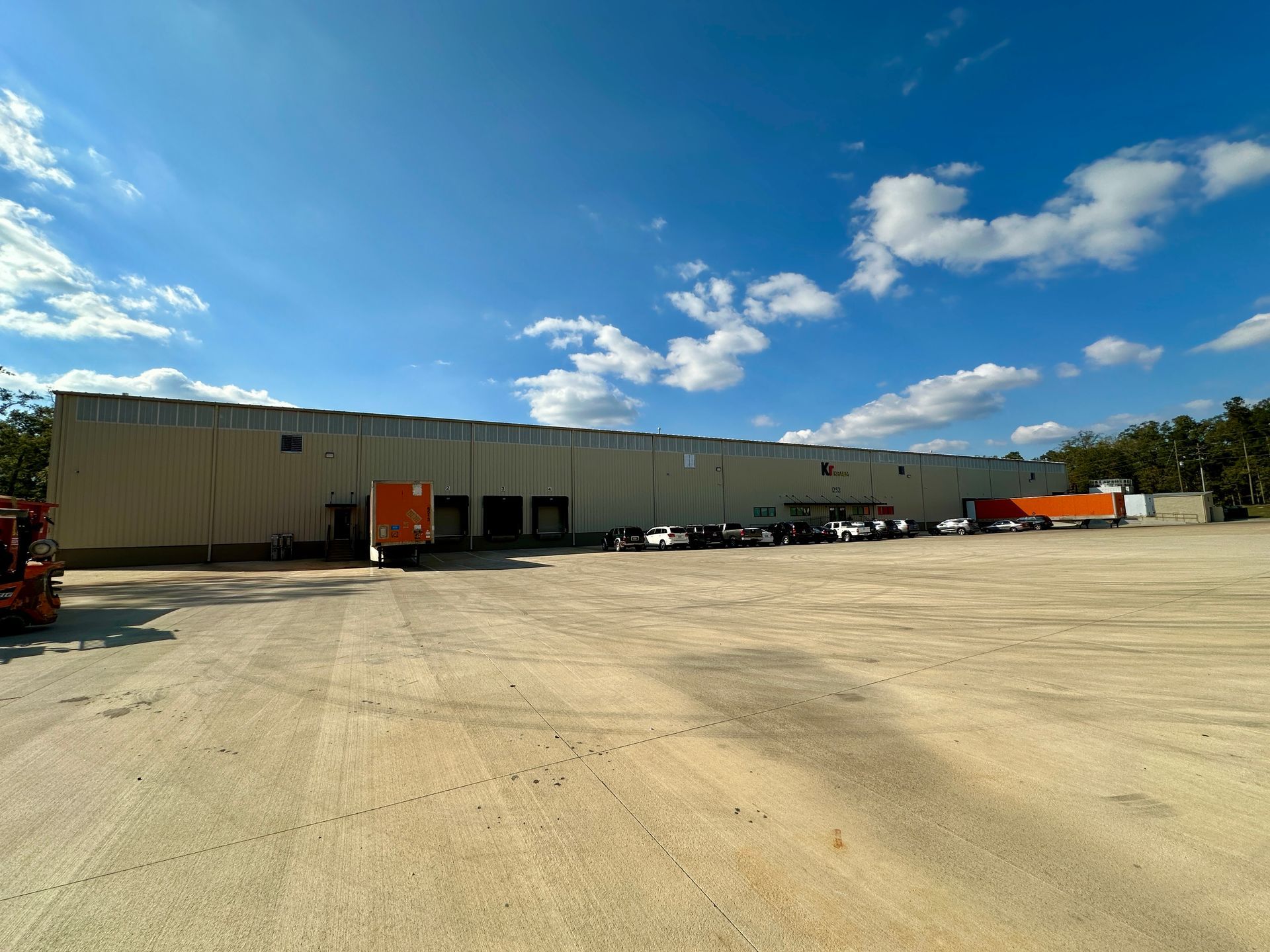 A large warehouse with a lot of trucks parked in front of it