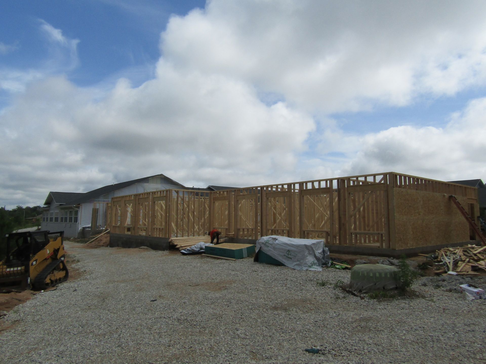 A large building is being built in a gravel lot.
